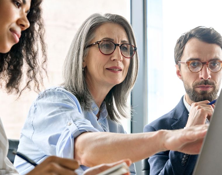 Three professionals collaborating around a laptop in a modern office setting- Neutrinos