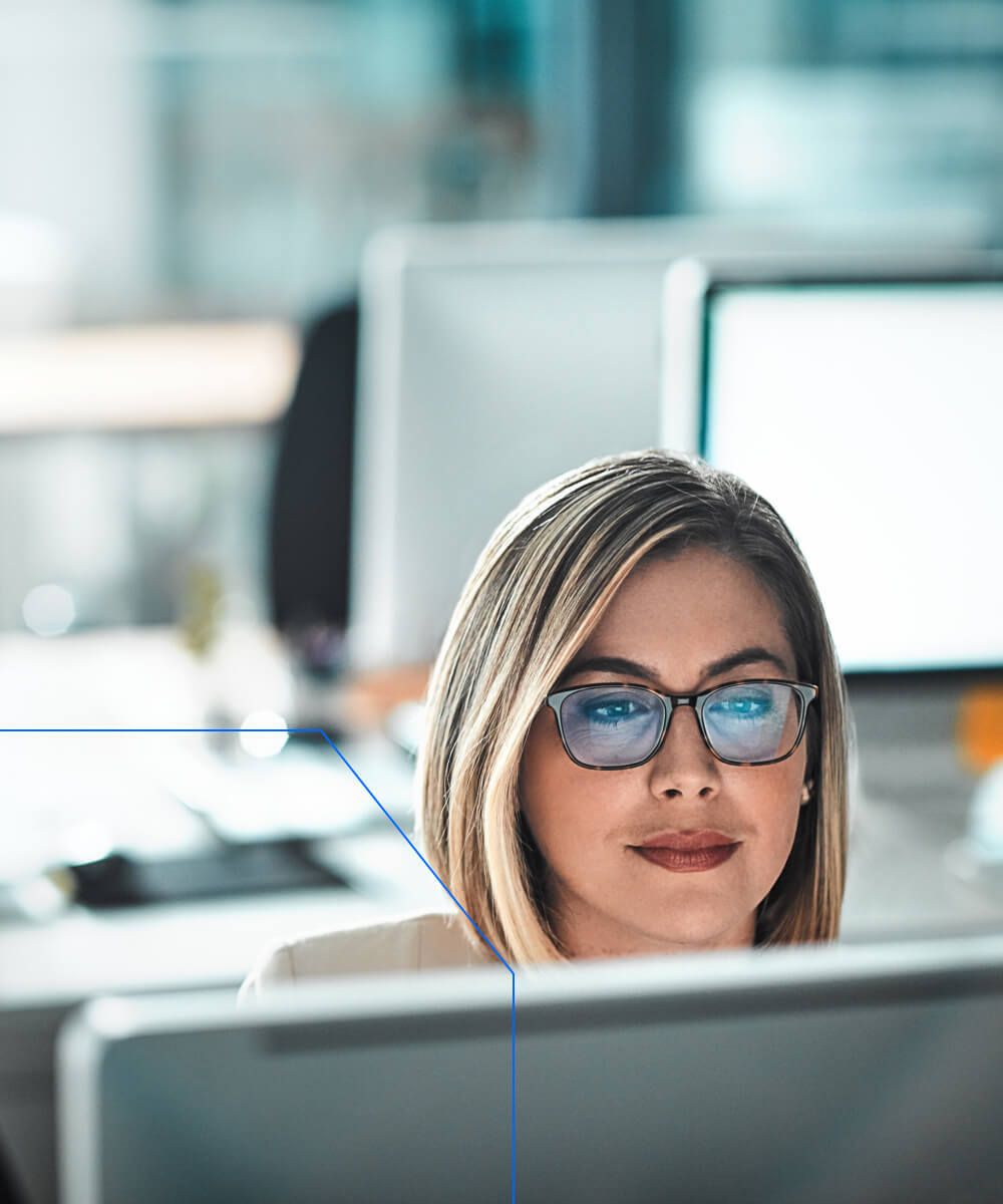Focused professional woman with glasses working at a computer in a modern office setting - Neutrinos