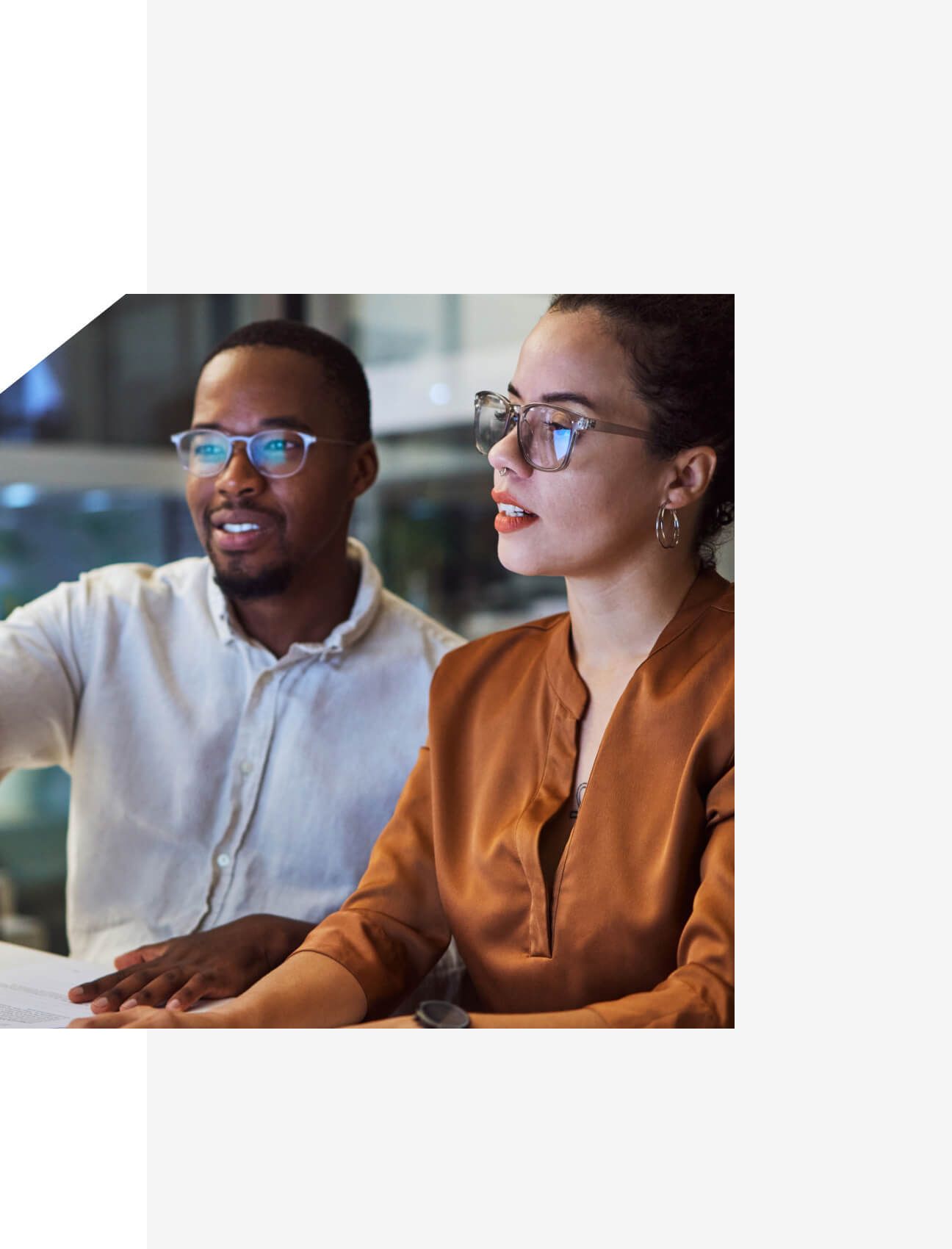 Two professionals in discussion at a modern office desk, reviewing content on a screen-Neutrinos