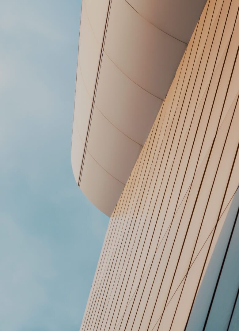 Modern curved architectural facade with vertical panels against a blue sky-Neutrinos