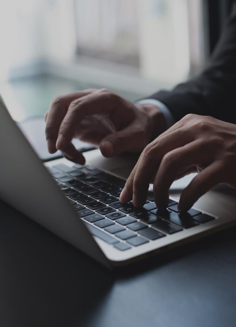 Close-up of hands typing on a laptop keyboard during work in a professional environment - Neutrinos